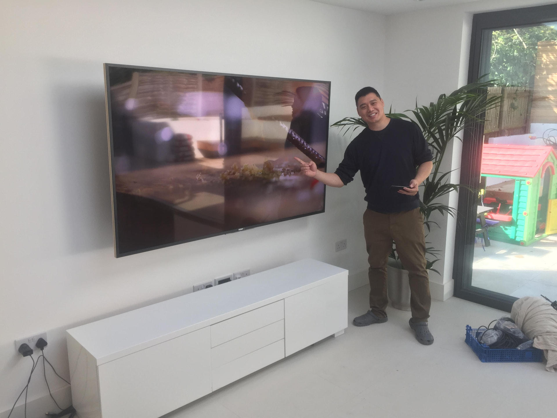 Large flat-screen TV professionally wall mounted above a white media unit
