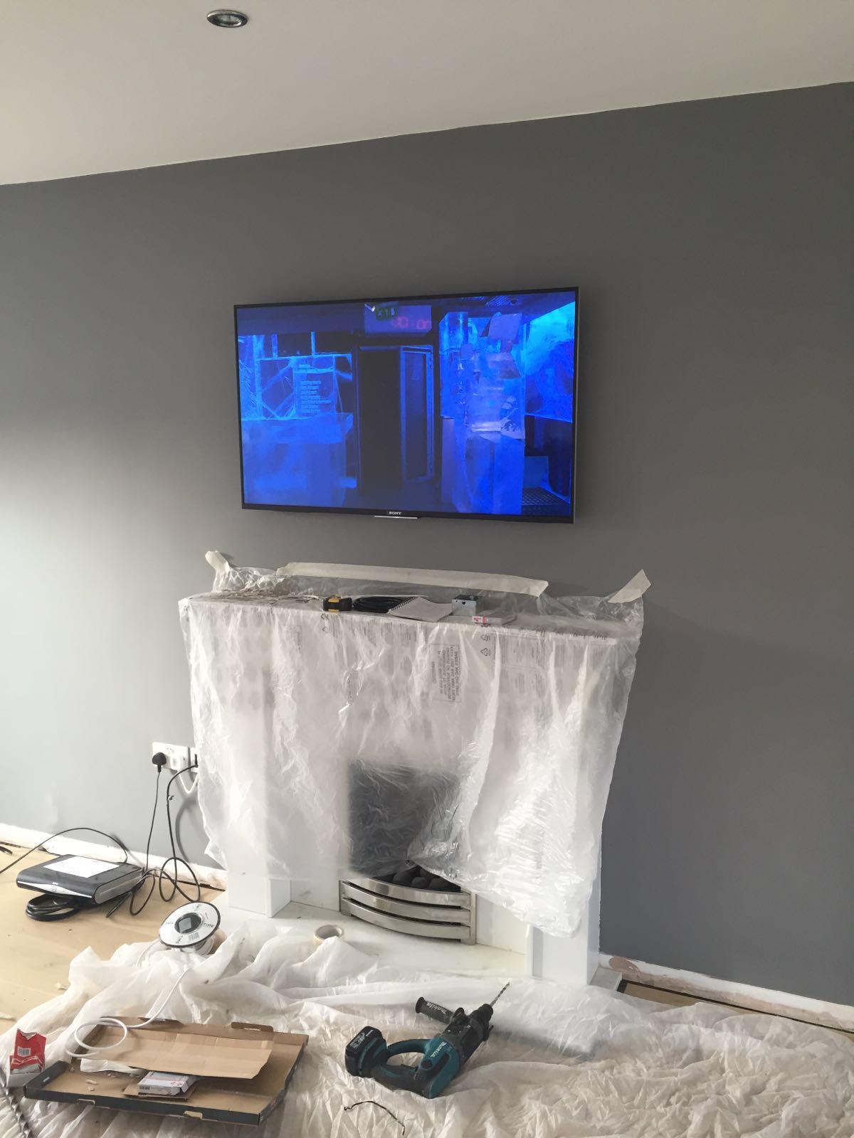 Completed TV wall mount above a fireplace with protective dust sheeting