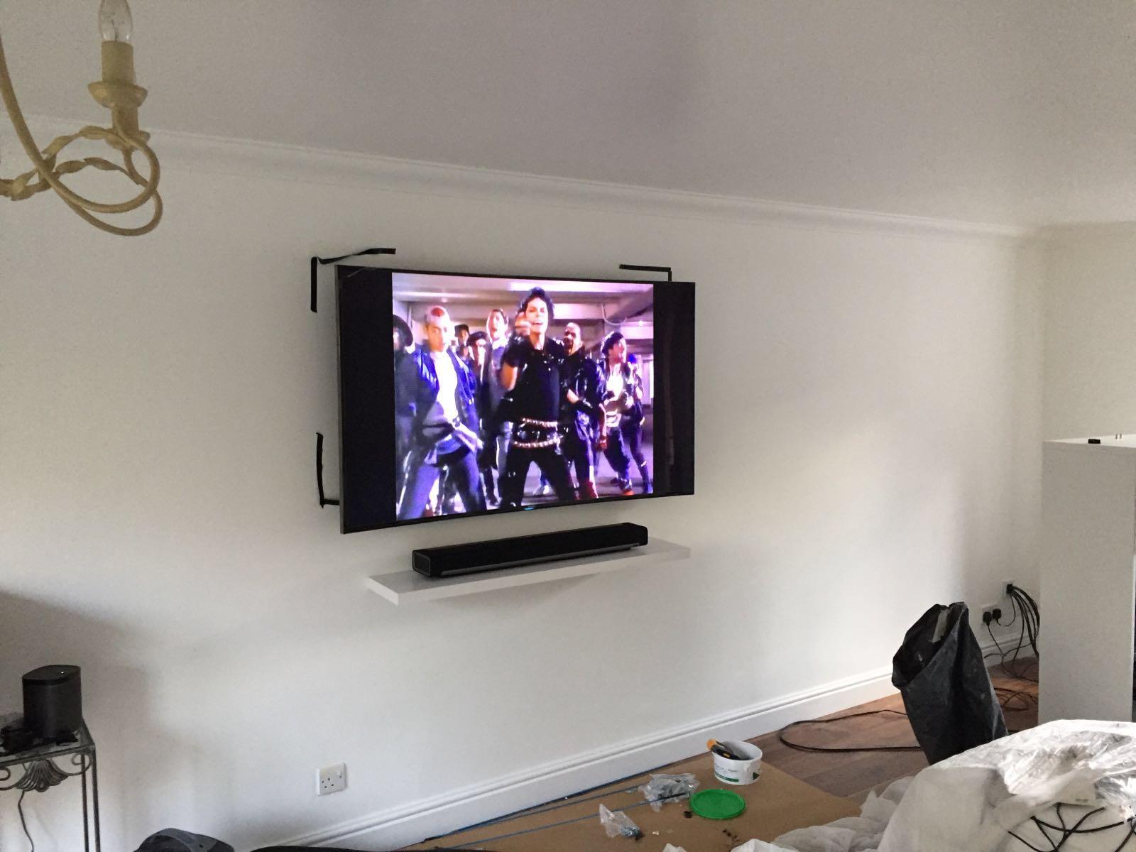 TV wall mounted above a white floating shelf in a modern living room