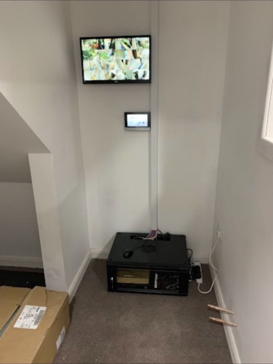 Completed CCTV install with multi-camera view on a wall-mounted monitor and recorder below